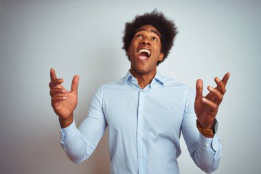 Afro saçlı, beyaz arka plan üzerine şık gömlek giyen, deli gibi bağıran, agresif ifade ve kollarıyla bağıran Afrikalı genç bir Amerikalı. Hayal kırıklığı konsepti.