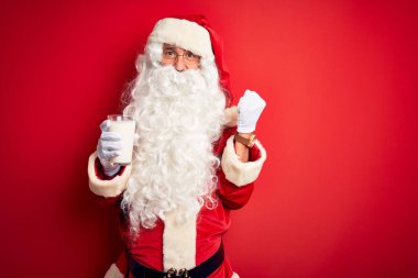 Son sınıf öğrencisi Noel Baba kostümü giyiyor. Kırmızı arka planda bir bardak süt taşıyor. Gururla bağırıyor, zaferi ve başarıyı kutluyor.