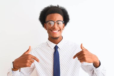Genç afro-amerikan iş adamı kravat takıyor ve gözlük takıyor izole beyaz arka planda kendine güler yüzlü görünüyor, kendini gururlu ve mutlu parmaklarıyla gösteriyor..