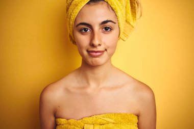 Sarıya boyanmış bir arka planda havlu takan genç ve güzel bir kadın zeki bir yüz ifadesiyle ciddi düşünüyor.