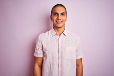 Pembe izole edilmiş arka planda zarif gömlek giyen yakışıklı bir adam. Yüzünde mutlu ve havalı bir gülümseme var. Şanslı kişi..