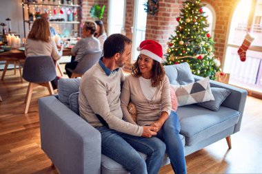 Noel arifesini evde geleneksel yemek ve dekorasyonla kutlayan aile ve arkadaşlar kanepede oturup romantik yaşlı çiftler gibi sohbet ediyorlar.