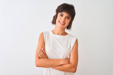 İzole edilmiş beyaz arka plan üzerinde sıradan tişörtler giyen genç ve güzel bir kadın kollarını kavuşturup kameraya bakarken gülümsüyor. Pozitif kişi.