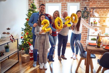 Mutlu ve kendinden emin gülümseyen güzel bir aile. Noel 'i kutlamak için elinde balonlarla dikiliyorum.