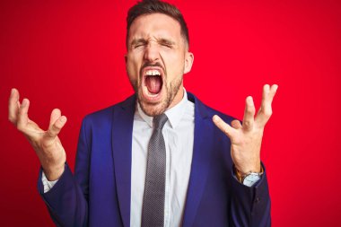 Genç ve yakışıklı iş adamı, kırmızı arka planda, çılgın ve başarının kutlamalarını kollarını kaldırarak ve gözlerini kapatarak heyecanla bağırarak yapıyor. Kazanan konsept