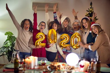 Mutlu ve kendinden emin gülümseyen güzel bir kadın grubu. Evde 2020 balon tutan noel ağacı etrafında poz vermek