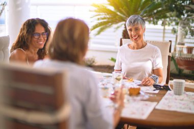 Genç ve güzel bir kız mutlu ve kendinden emin bir şekilde terasta oturmuş bir fincan kahve içiyor.