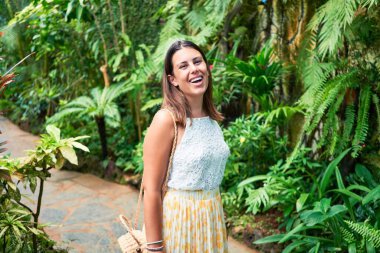 Güneşli bir yaz gününde, kelebek bahçesinde mutlu ve neşeli gülümseyen güzel bir kadın.