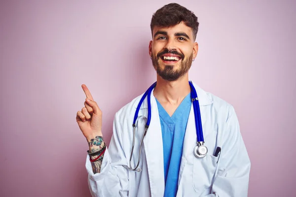Młody Lekarz Tatuażem Noszący Stetoskop Stojący Nad Odizolowanym Różowym Tłem — Zdjęcie stockowe