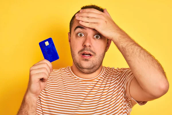 Young Man Holding Blue Credit Card Standing Isolated Yellow Background — Stock Photo, Image