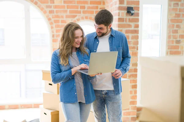 Jong paar met behulp van computer laptop staande op een kamer rond auto — Stockfoto