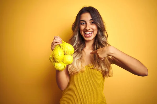 Giovane Bella Donna Tenendo Rete Limoni Sfondo Giallo Isolato Con — Foto Stock