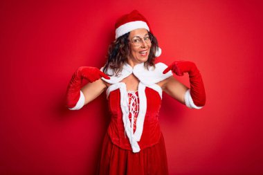 Orta yaşlı, güzel bir kadın. Noel Baba kostümü giyiyor. İzole edilmiş kırmızı arka planda..