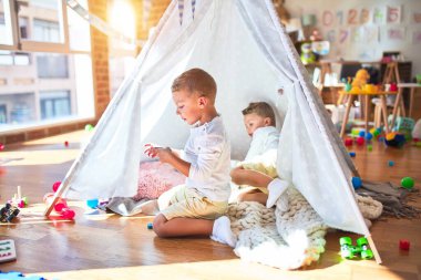 Anaokulunda bir sürü oyuncağın etrafında oynayan sevimli sarışın ikizler.