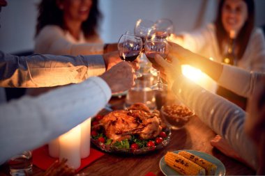 Aile ve arkadaşlar Noel arifesini geleneksel yemek ve dekorasyonla birlikte evde yemek yiyorlar. Hep birlikte masaya oturuyorlar.