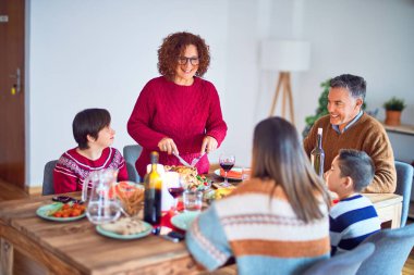 Mutlu ve kendinden emin gülümseyen güzel bir aile. Kavrulmuş hindilerden biri evde Noel 'i kutluyor.