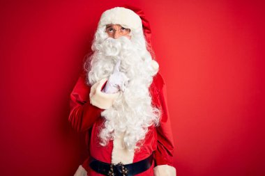 Orta yaşlı, yakışıklı, Noel Baba kostümü giyen, izole edilmiş kırmızı arka plan üzerinde duran, parmakları çenesinde şüpheyi düşünen ve kafasını kaldırıp,