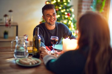 Mutlu ve kendinden emin gülümseyen genç bir çift. Evde Noel 'i kutlamak için yemek yiyorum.