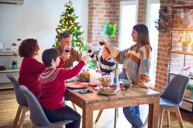 Mutlu ve kendinden emin gülümseyen güzel bir aile. Bir tanesi elinde şarap bardağıyla evde Noel 'i kutlarken konuşuyordu.