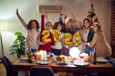 Mutlu ve kendinden emin gülümseyen güzel bir kadın grubu. Evde 2020 balon tutan noel ağacı etrafında poz vermek