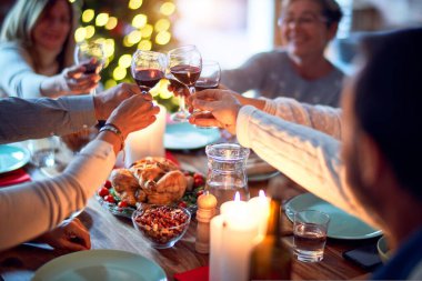 Aile ve arkadaşlar Noel arifesini geleneksel yemek ve dekorasyonla birlikte evde yemek yiyorlar. Hep birlikte masaya oturuyorlar.