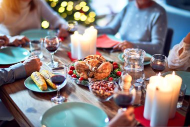 Aile ve arkadaşlar Noel arifesini geleneksel yemek ve dekorasyonla birlikte evde yemek yiyorlar. Hep birlikte masaya oturuyorlar.