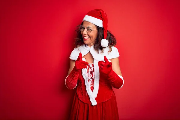 中年美女穿着圣诞老人的服装 站在孤立的红色背景上 手指指向镜头 脸上洋溢着喜庆可笑的表情 好的能量和活力 — 图库照片