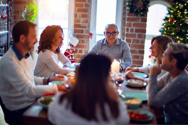 Family and friends dining at home celebrating christmas eve with traditional food and decoration, all sitting on the table together