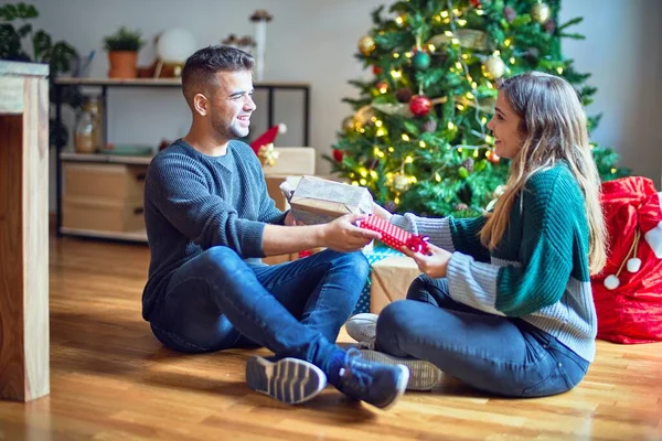 年轻漂亮的夫妇面带微笑 既快乐又自信 男人给家里圣诞树旁的女人一个惊喜 — 图库照片