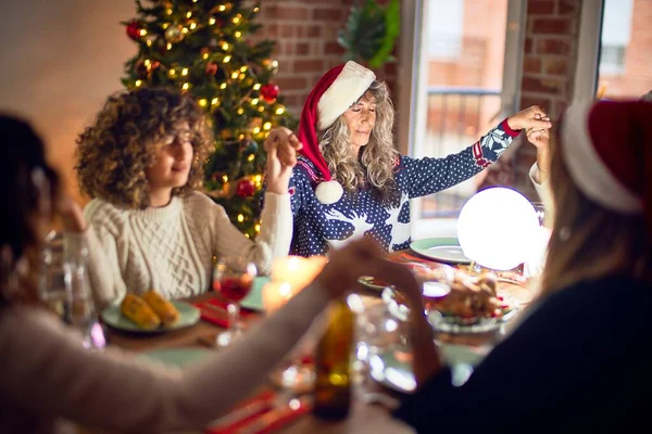 Beautiful group of women smiling happy and confident. Taking hands praying together celebrating christmas at home