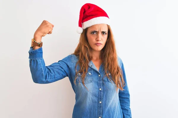 若いです美しい赤毛女性身に着けているクリスマスの帽子隔離された背景上に強い人ショー腕の筋肉 自信と力の誇り — ストック写真