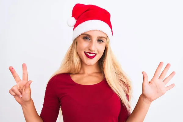 若いです美しいです女性身に着けていますクリスマスサンタ帽子上の隔離された白い背景ショーと指差し込み指番号8ながら笑顔自信と幸せ — ストック写真