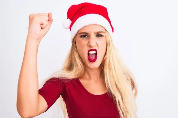 年轻美丽的女人戴着圣诞圣诞礼帽 披着孤立的白色背景 怒气冲冲地举起拳头 怒气冲冲地喊着 愤怒和好斗的概念 — 图库照片