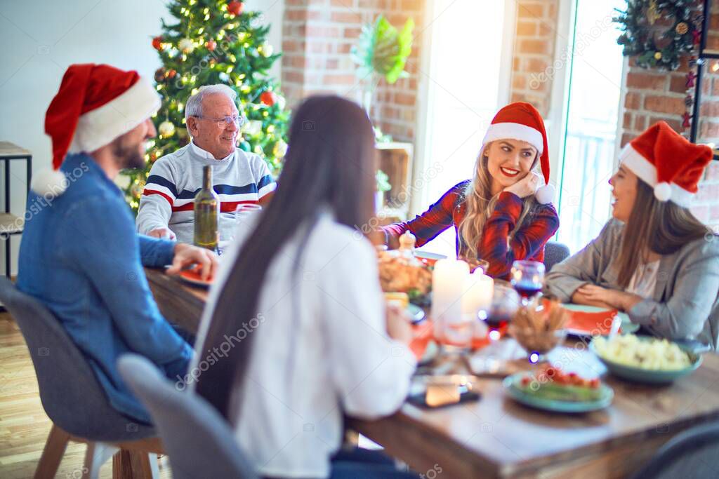 Beautiful family wearing santa claus hat meeting smiling happy and confident. Eating roasted turkey celebrating Christmas at home