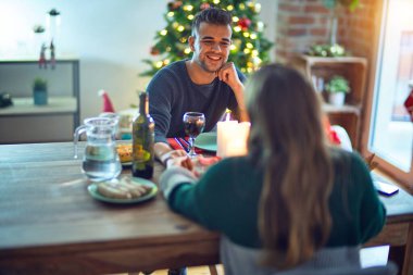 Mutlu ve kendinden emin gülümseyen genç bir çift. Evde Noel 'i kutlamak için yemek yiyorum.