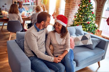 Noel arifesini evde geleneksel yemek ve dekorasyonla kutlayan aile ve arkadaşlar kanepede oturup romantik yaşlı çiftler gibi sohbet ediyorlar.