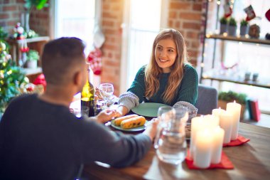 Mutlu ve kendinden emin gülümseyen genç bir çift. Evde Noel 'i kutlamak için yemek yiyorum.