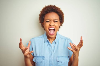 Genç güzel Afrikalı Amerikan kadın üzerinde afro saç ile izole arka plan çılgın ve deli çığlık ve saldırgan ifade ve silah ile bağırdı kaldırdı. Hayal kırıklığı kavramı.