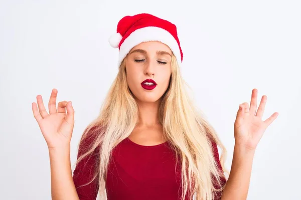 孤立した白い背景の上にクリスマスのサンタの帽子を身に着けている若い美しい女性は指で瞑想のジェスチャーをして閉じ目でリラックスして笑顔 ヨガのコンセプト — ストック写真