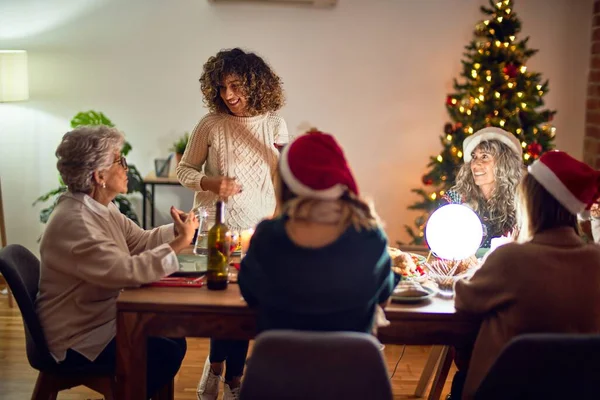 女性の美しいグループの幸せと自信を笑顔 自宅でクリスマスを祝うワインのスピーチのカップを保持している彼らの上に — ストック写真