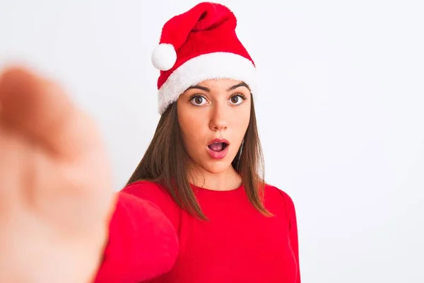 戴着圣诞圣诞圣诞礼帽的女孩在孤独的白色背景下 用相机拍下自己的照片 吓得面无血色 吓得满脸都是恐惧和兴奋的表情 — 图库照片