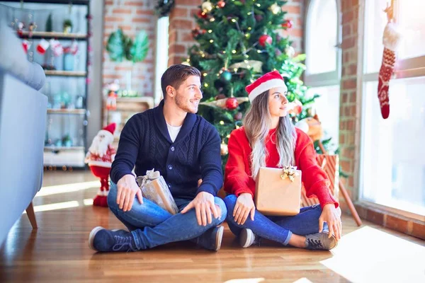 Casal Jovem Vestindo Chapéu Papai Noel Sentado Chão Torno Árvore — Fotografia de Stock