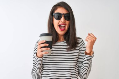 Güneş gözlüğü takan Çinli bir kadın izole edilmiş beyaz arka planda kahve içerken gururla bağırıyor, zaferi ve başarıyı kutluyor çok heyecanlı, coşkulu bir duygu.