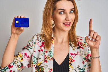 Kafkasyalı iş kadını kredi kartını soyutlanmış bir arkaplanda tutarken bir fikre ya da soru işaretine şaşırdı.