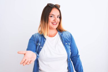 Güzel bir kadın kot gömlek giyer, beyaz arka planda durur mutlu bir gülümsemeyle avuç içi yardım eli uzatır ve kabul eder..