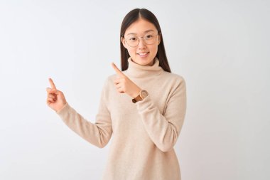 Balıkçı yaka kazak ve gözlük takan genç Çinli kadın izole edilmiş beyaz arka planda gülümsüyor ve kameraya bakıyor..