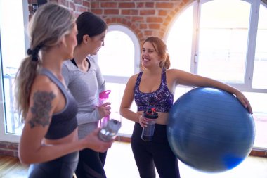 Mutlu gülümseyen genç ve güzel bir spor kadını grubu. Spor salonunda yoga yaptıktan sonra yüzünde gülümsemeyle ayakta durmak.