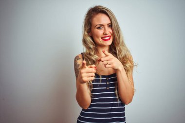 Çizgili tişört giyen genç ve güzel bir kadın beyaz izole edilmiş arka plan üzerinde durmuş mutlu ve komik yüzlü parmaklarını kameraya doğrultuyor. İyi enerji ve titreşimler.