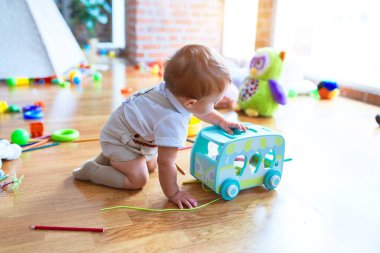 Anaokulunda bir sürü oyuncakla oynayan sevimli bir çocuk.