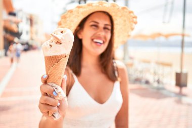 Yazın güneşli bir gününde kumsalda dondurma yiyen güzel bir kadın.